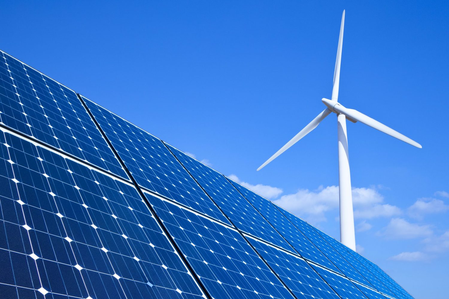 Solar panels and wind turbine against blue sky